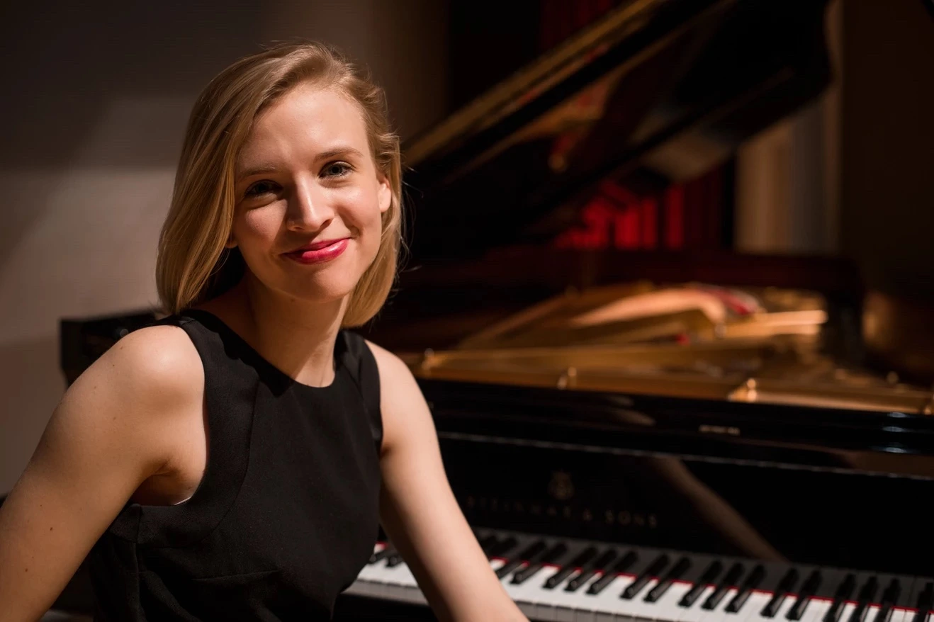 Caroline sitting at piano smiling